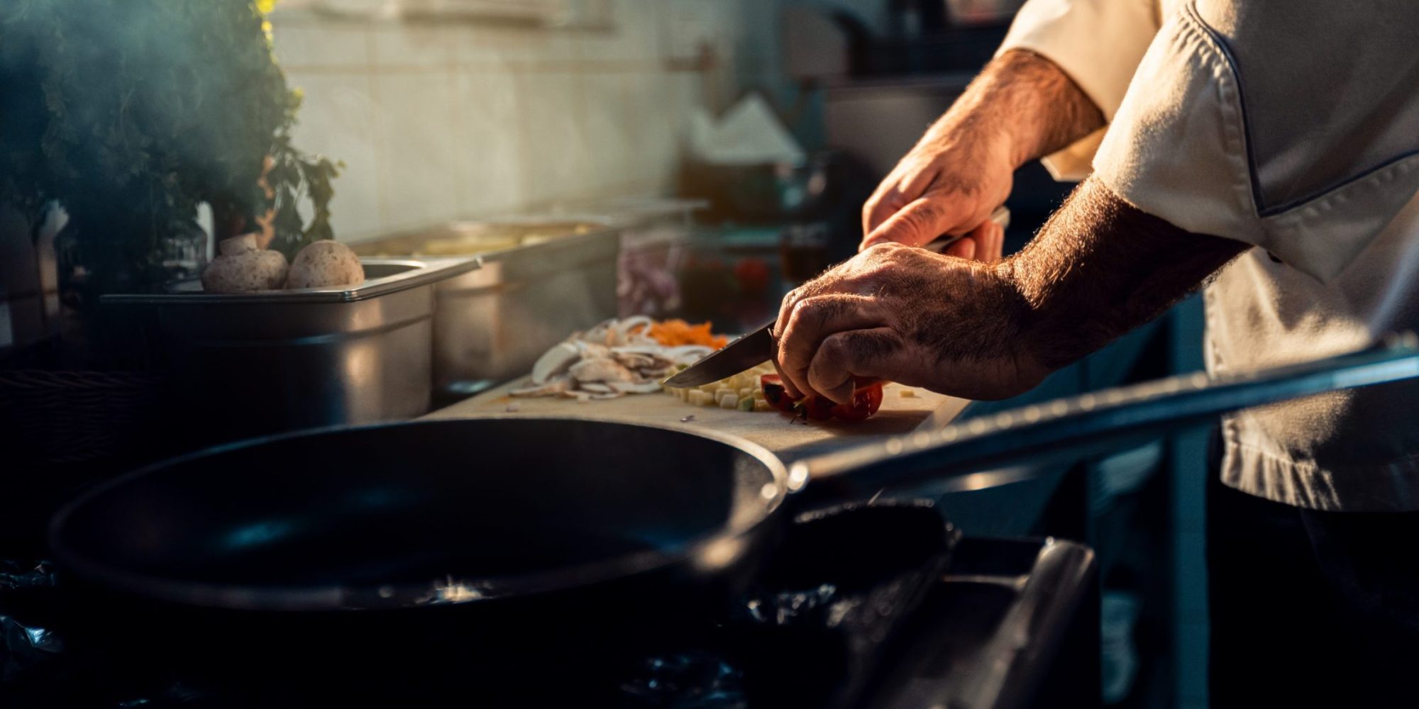 Chef cooking in a commercial kitchen choping vegetable.