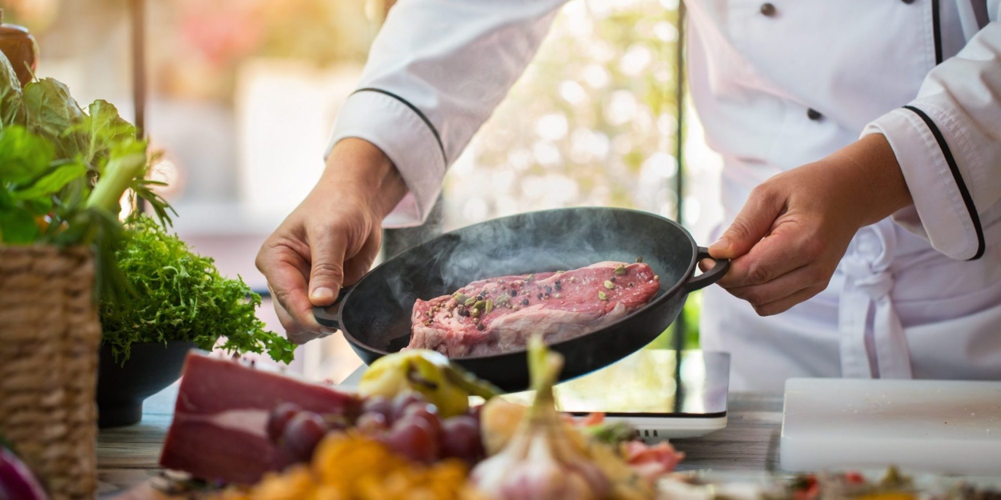 Raw meat on black pan. Man's hands hold frying pan. Professional cook in the kitchen. Best recipe of beef.